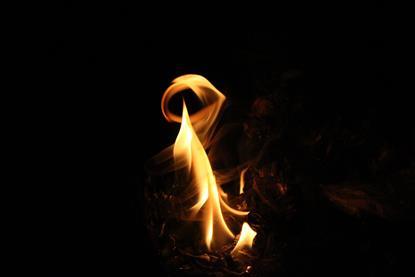 A close-up photograph of some small yellow flames burning against a dark background