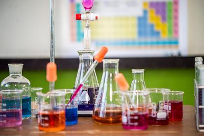Assorted practical chemistry equipment. Different beakers have different coloured liquids in them.