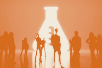 People standing a dark room with a giant lit conical flask symbol