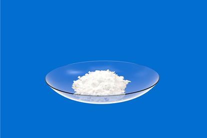 An edited photograph of white lead chloride in a glass dish against a plain blue background