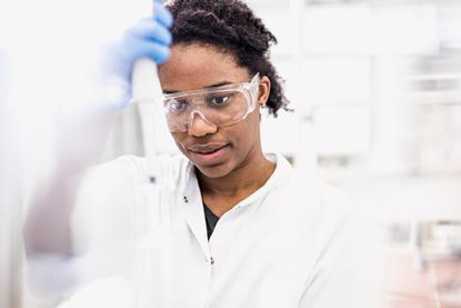 A chemist wearing protective eyewear and a white lab coat