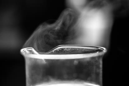 A photograph of a glass beaker containing a liquid, with a gas visibly rising from the top