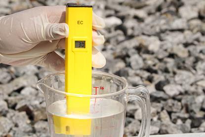 A yellow conductivity meter submerged in a measuring jug of clear liquid