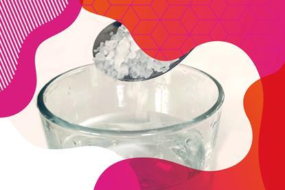 Photo of salt on a spoon, held above a glass of water