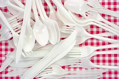 A pile of white plastic cutlery on a red and white checkered tablecloth