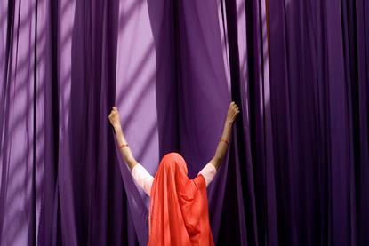 A photograph of a woman sorting drying mauve fabric