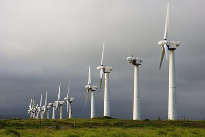 A line of old broken wind turbines under a grey sky