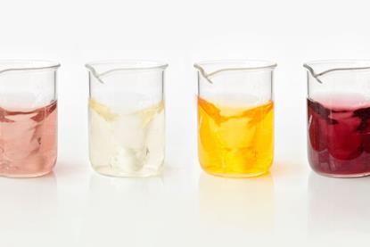 Series of four glass beakers, each containing a different coloured solution