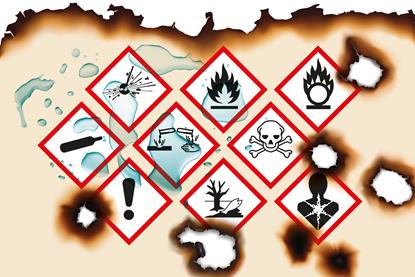 A piece of paper with warning symbols on that has been burned and splashed