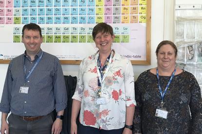 Three people standing in front of a periodic table
