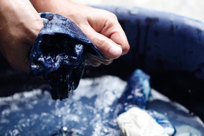 Water, and fabric, dyed indigo. With hands wringing out water