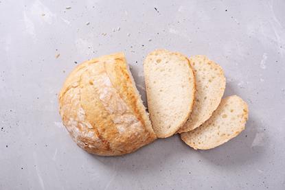 A round loaf of white bread partly cut to produce three slices