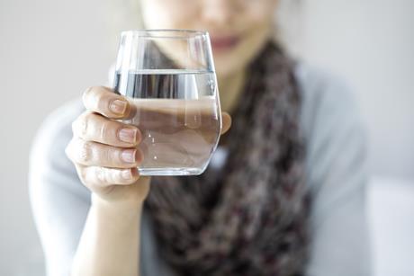 A lady holding a glass of clean drinking water