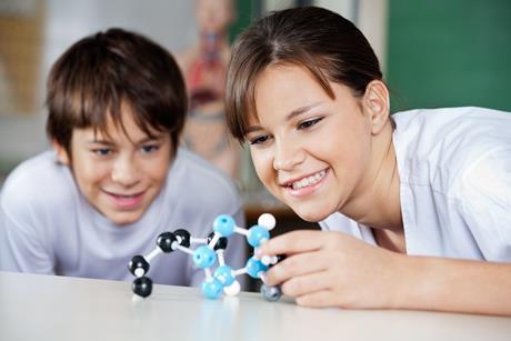 Teenage schoolchildren examining molecular structure at desk in lab