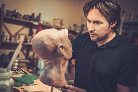 A man working on a silicone mask for a film in a special effects workshop