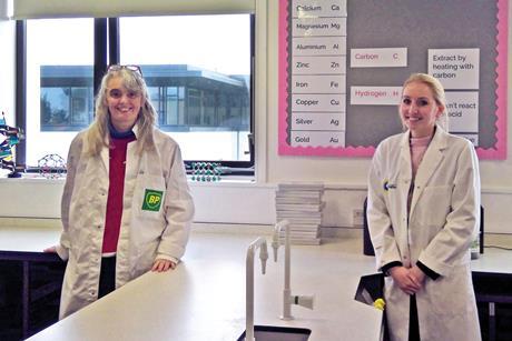 Two teachers wearing lab coats in a science classroom