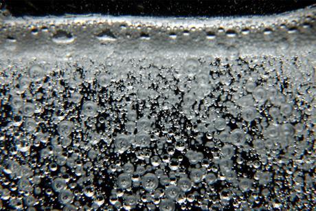 Lots of small bubbles in a clear liquid rising to the surface