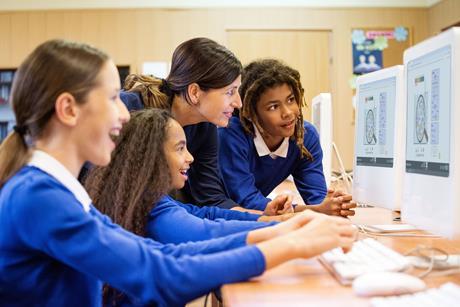 A teacher in a computer lab with some students looking at a acid-base simulation on the computer screens