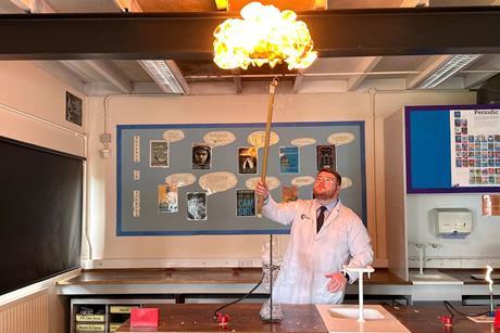 A science teacher using a long splint to light some hydrogen bubbles in a large fireball