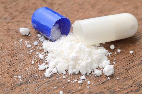 Photo of white powder spilling out of a drug capsule