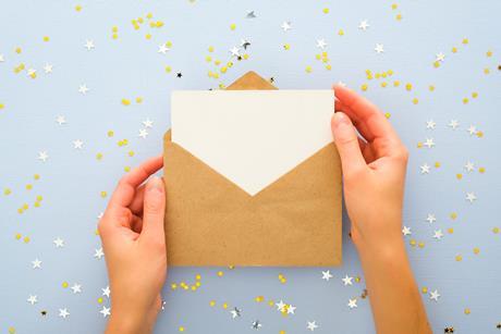 An image of someone opening a golden envelope surrounded by confetti
