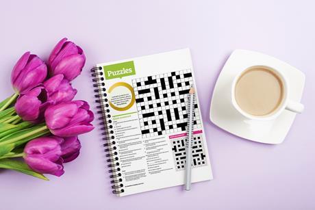 A bunch of pink tulips, a cup of tea and a puzzle book and pencil
