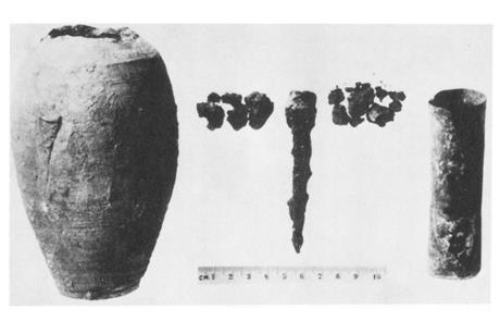 An old black and white photo of a cracked clay jar and some metal components