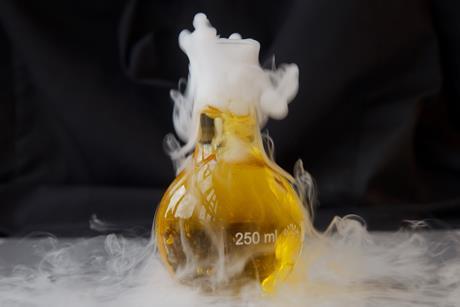 A conical flask of yellow liquid bubbles with a heavy white smoke