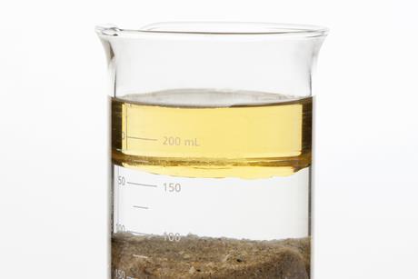 Photo of oil, water and sand separated in a beaker