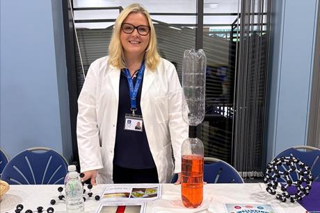 Lynsey Findlay wearing a lab coat manning the science club table at a school fair
