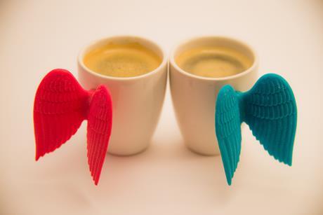 An image showing two cups of coffee with Cupid wings on them