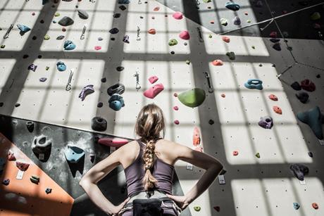 A photo of a woman planning her route up an indoor rock climbing wall