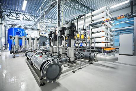 Inside a reverse osmosis plant with a collection of pipes and machinery.