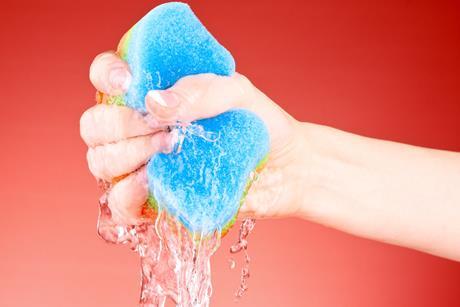 A hand squeezing water from a sponge