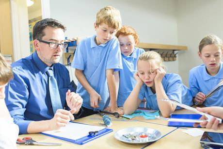 Group of primary pupils watch their teacher do a science demonstration using a candle
