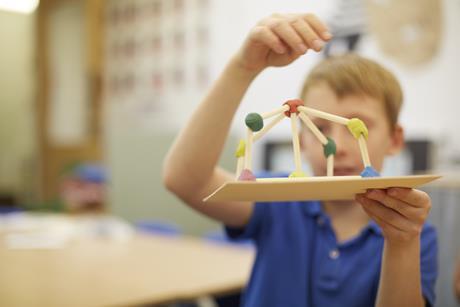 Primary school pupil shows off a model they've made from wood and plasticine