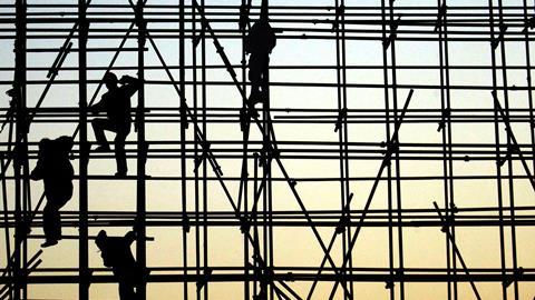 Workers climbing scaffolding in silhouette