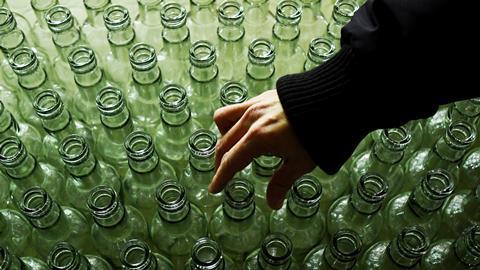 A hand examines clear glass bottles