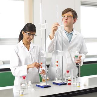 A photo of two teenagers doing a titration experiment