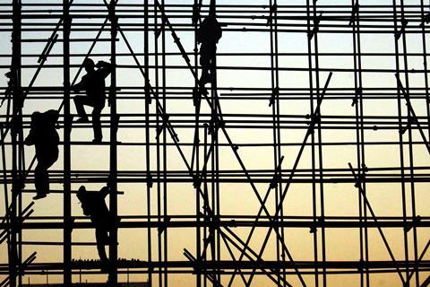 Workers climbing scaffolding in silhouette