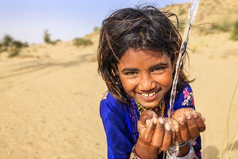 Little Indian girl smiling, clear water pouring into her hands