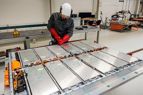 A worker in protective gear with EV batteries