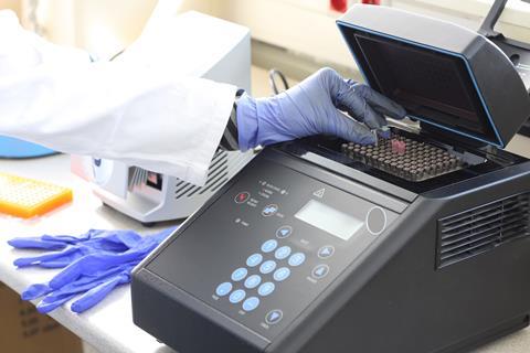 A sciencist puts a tube into a PCR machine
