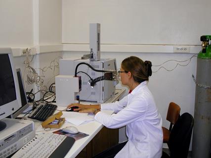 An image showing a woman in a lab coat seated at a desk using a gas chromatography olfactometer