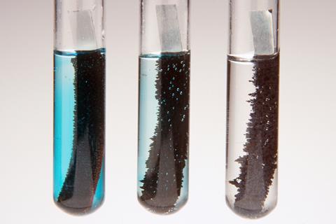 Three test tubes containing a liquid and metal. Moving from left to right the liquid loses its blue colour and the metal becomes furrier with a black substance