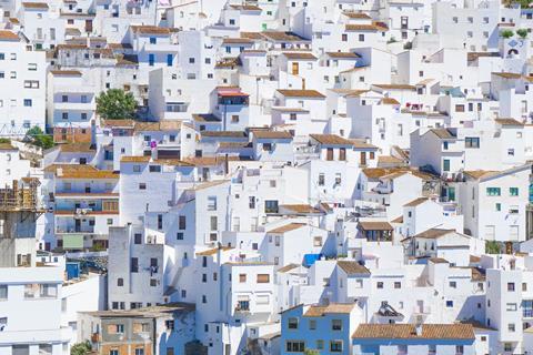 A photo of houses painted white on the side of a hill