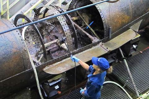A woman spraying a rusty old submarine