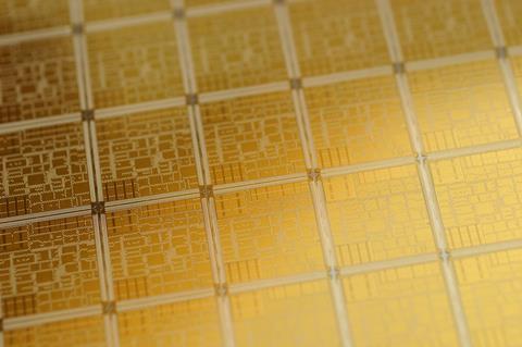 A close up photo of an electronic chip wafer with gold components