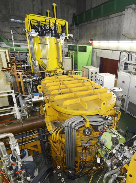 A large yellow machine with cables, pipes, tubes and other equipment attached
