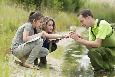 Students making notes and observing by a pond